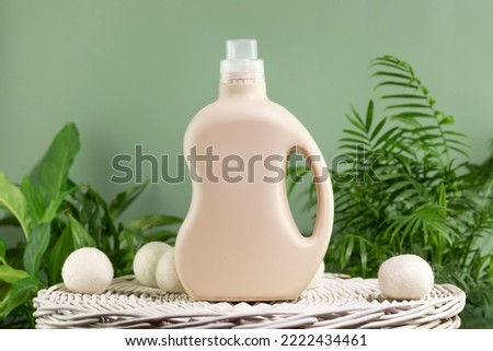 Natural laundry detergent mockup. Washing detergent concept with bottles of washing gel or fabric softener on a white laundry basket on a green background with green leaves. Laundry day