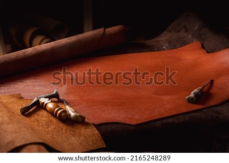 Natural leather brown color dark background with tools of shoes maker, copy space.