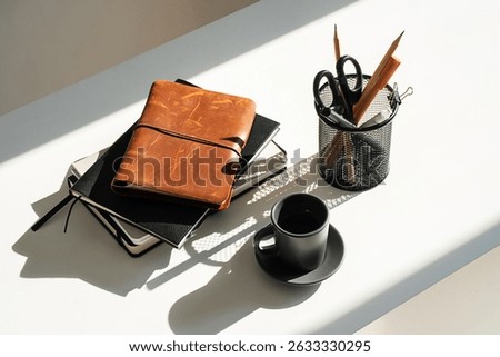 Natural Light Illuminates the Office Desk with Notebooks, Pen Holder and Coffee Cup. Modern Workspace Scene.