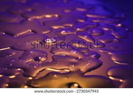 Natural liquid forms positioned on a dark, smooth surface. Abstract texture enriched with surface tension and macro details. High-contrast liquid photography suitable for modern designs, tech backgrounds, and minimalist creative visuals.