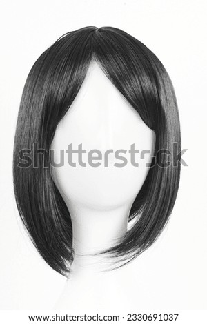 Natural looking black wig on white mannequin head. Medium length straight hair with bangs on the metal wig holder isolated on white background, front view