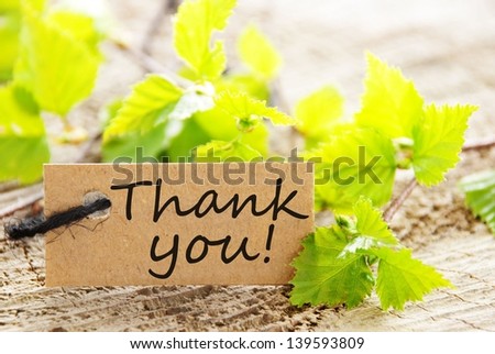 a natural looking label with thank you and green leaves and wood as background