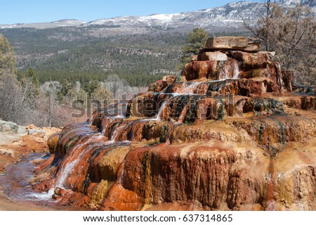 Natural mineral spring cascading down the colorful steps of mineral deposits in New Mexico.
