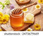 Natural organic honey in glass jar, honey dipper and honeycombs are near. Natural food background.