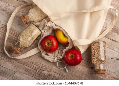 Natural, Plastic Free Recycled Textile Produce Bag For Carrying Fruit Or Vegetables On A Wooden Surface. Reusable Cotton Textile Bags And Glass Small Containers For Zero Waste Shopping Or Storage.