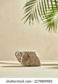 Natural podium of stone with palm tree. Rock, leaves, shadow, beige bottom and background. Minimalistic pedestal for cosmetics.
