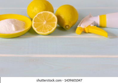 Natural Products For Eco Friendly Cleaning. Lemon, Baking Soda And Vinegar For Eco Housekeeping. All Objects, Lemon, Bowl, Pump Sprayer  Are In Yellow Color. Blue Wooden Background.