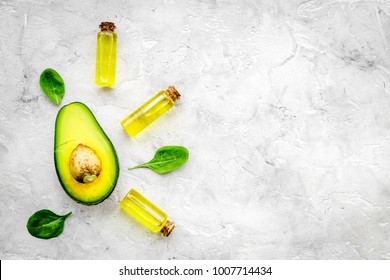 Natural Products For Skin Care. Avocado Oil In Bottles Near Sliced Avocado On Grey Background Top View Copy Space