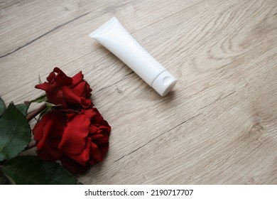 Natural Red Rose Flower Hair Products For Healthy Hair. Blank White Squeeze Tube Of Shampoo With Hair Serum Bottle And Fresh Organic Roses On Wooden Background. Beauty Herbal Haircare Concept