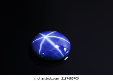 Natural rich blue star sapphire cabochone oval loose gemstone setting for making jewelry. Black background isolated. Diffusion treated, heated, color enhanced gem. Gemology, mineralogy. Close up. - Shutterstock ID 2197685705