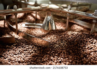 Natural roasted coffee beans mixing in mixer of industrial roasting machine on factory. Coffee process making and production on export. Small business. Modern automated manufacturing equipment
