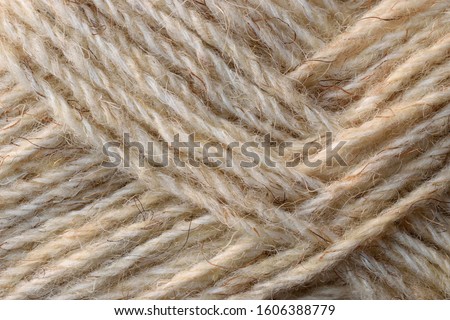 Natural sheep coarse wool yarn texture. Undyed light brown yarn background. Closeup