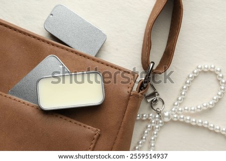 Natural solid perfume in containers and leather bag on light table, flat lay