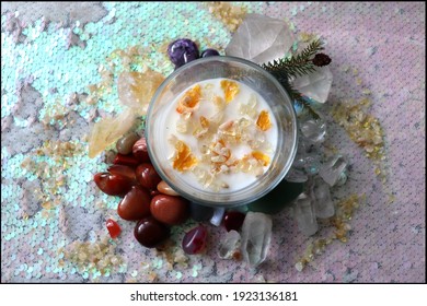 Natural soy candle with colorful crystals around and dried fruits, perfect for wiccan relaxation ritual, reiki and balancing chakras