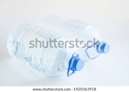 Natural Spring Water in five liter bottles on the white surface with own with nylon packing.