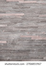 Natural stone wall cladding with a rough, stacked texture in grey and pinkish tones. Perfect as a background for architectural design or home decor concepts.