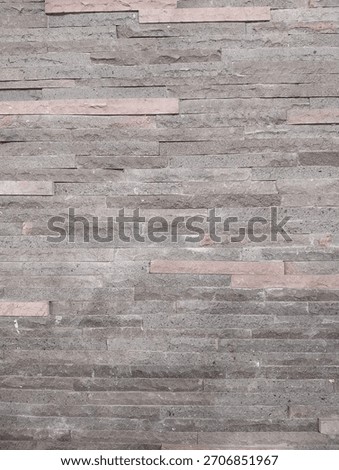 Natural stone wall cladding with a rough, stacked texture in grey and pinkish tones. Perfect as a background for architectural design or home decor concepts.