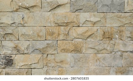 natural stone wall featuring rectangular sandstone blocks in rustic beige, yellow and brown tones