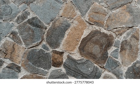 Natural stone wall texture background with various irregular shapes and earthy colors. Close-up of a rustic rock surface background for construction and architectural design