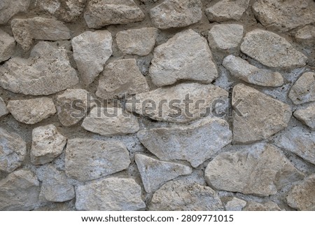 Natural stone wall texture with irregular rocks and cement mortar for rustic architectural background.