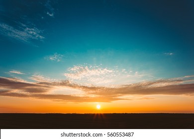 Natural Sunset Sunrise Over Field Or Meadow. Bright Dramatic Sky And Dark Ground. Countryside Landscape Under Scenic Colorful Sky At Sunset Dawn Sunrise. Sun Over Skyline, Horizon. Warm Colours. - Shutterstock ID 560553487