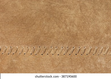 Natural tan color suede texture with decorative stitch as background.