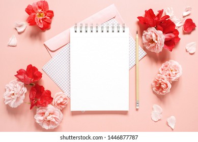 Natural template with blank notepad and various vintage roses on the pink background, top view