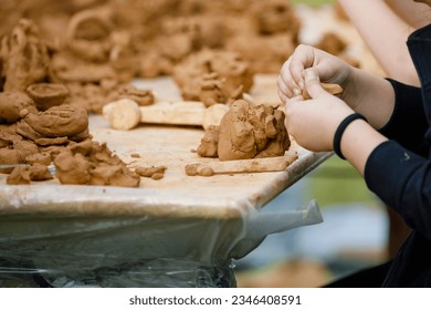 Natural terracotta clay piece held in hands. Wet clay material for sculpture or modeling lesson - Powered by Shutterstock