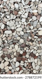 Natural texture background featuring a dense collection of oval-shaped river stones. 🪨