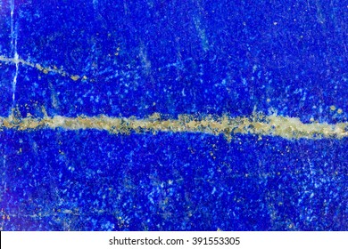 natural texture background - polished surface of lazurite mineral gemstone with vein of pyrite crystals close up