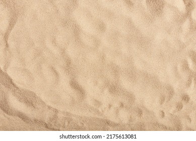 Natural texture: top view of beach sand, clear, clean and smooth. Minimalist background for summer concepts, travel, vacations and outdoor enjoyment.