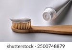 Natural toothpaste on a bamboo toothbrush. Bamboo toothbrush on white background. Wooden eco toothbrush.