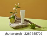 Natural vitamin C skin care product mockup with white plastic bottle unbranded on stone podium, fresh limes , flower branch and dry twig decorated on yellow background. Minimal style, space for design