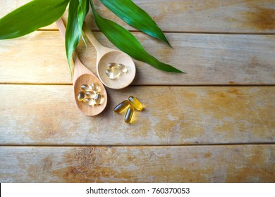 Natural Vitamins And Supplements In Wooden Spoons On Wood Table With Leaf Blackground.