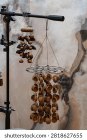 Natural walnut shell wind chime percussion musical instrument hanging on display with marble background