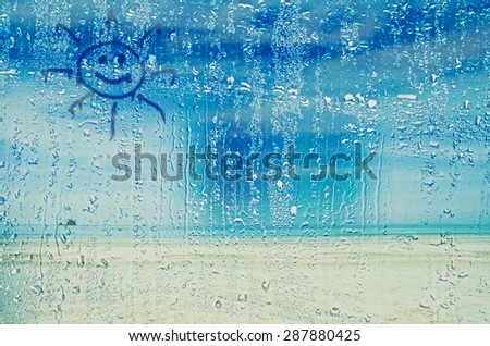 natural water drops on glass window with sun sign
