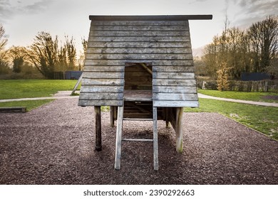 Natural wooden playhouse on timber stilts with ladder in outdoor natural public playground. Grass and trees in background. Soft, safe, wood chip floor surface underneath. Public children's play area.  - Powered by Shutterstock