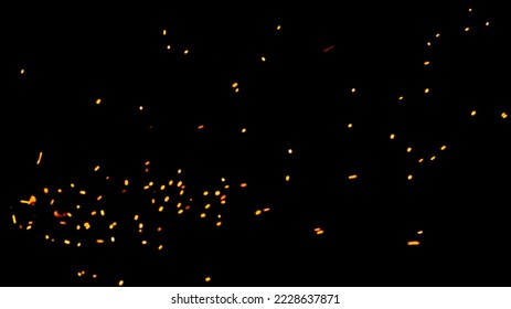 Natural yellow-hot sparks of fire on a black background, bright yellow bokeh from the fire. Particles of burning embers fly and glow isolated in the night sky.