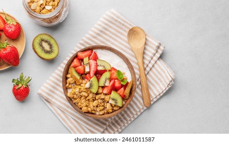 Natural yogurt with granola, kiwi and strawberries in a wooden bowl on a light background with fresh berries and fruits. Healthy and nutritious breakfast concept. Top view and copy space. - Powered by Shutterstock