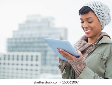 Natural young model in winter clothes using a tablet pc outside on a cloudy day - Powered by Shutterstock