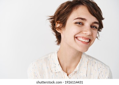 Natural young woman with happy smile, looking cheerful at camera, standing on white background. - Shutterstock ID 1926114431