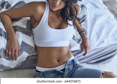 Naturally fit and beautiful. Close-up of young woman leaning on the bed while flooring at home           