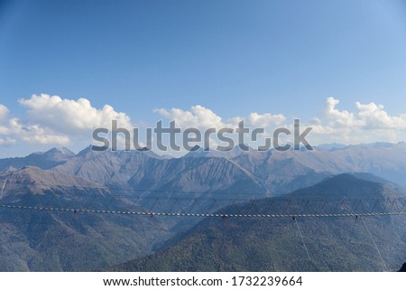nature, adventure and tourism concept - landscape of a suspension bridge in the mountains and blue sky