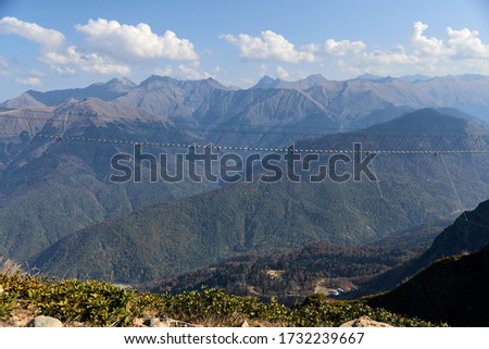 nature, adventure and tourism concept - landscape of a suspension bridge in the mountains and blue sky