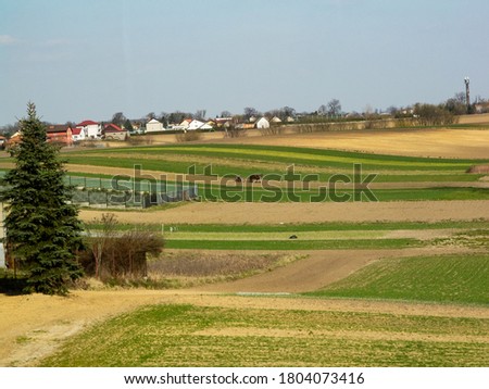 Similar – A tractor turns mown hay in a field in a small community