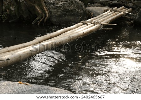Nature background. Bridge of bamboo that is above the river with clear flowing water. Scenic Relaxing Scenery