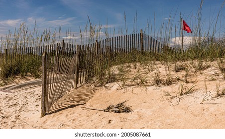 Nature background of wind fences and a danger flag on the sand dunes of a Florida island beach. - Powered by Shutterstock