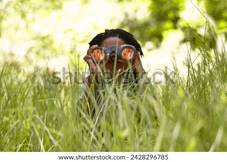 Nature, binoculars and child in grass for exploring in park on vacation, adventure or holiday. Travel, forest and young boy kid with equipment in lawn in outdoor field or woods on weekend trip.