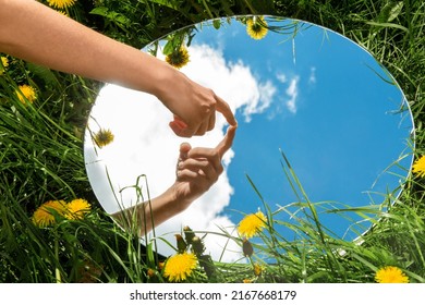 nature concept - hand touching sky reflection in round mirror on summer field - Shutterstock ID 2167668179