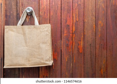 Nature eco-friendly grocery shopping bag, Jute tote bag with self handles hanging on red old wooden doll background - Powered by Shutterstock